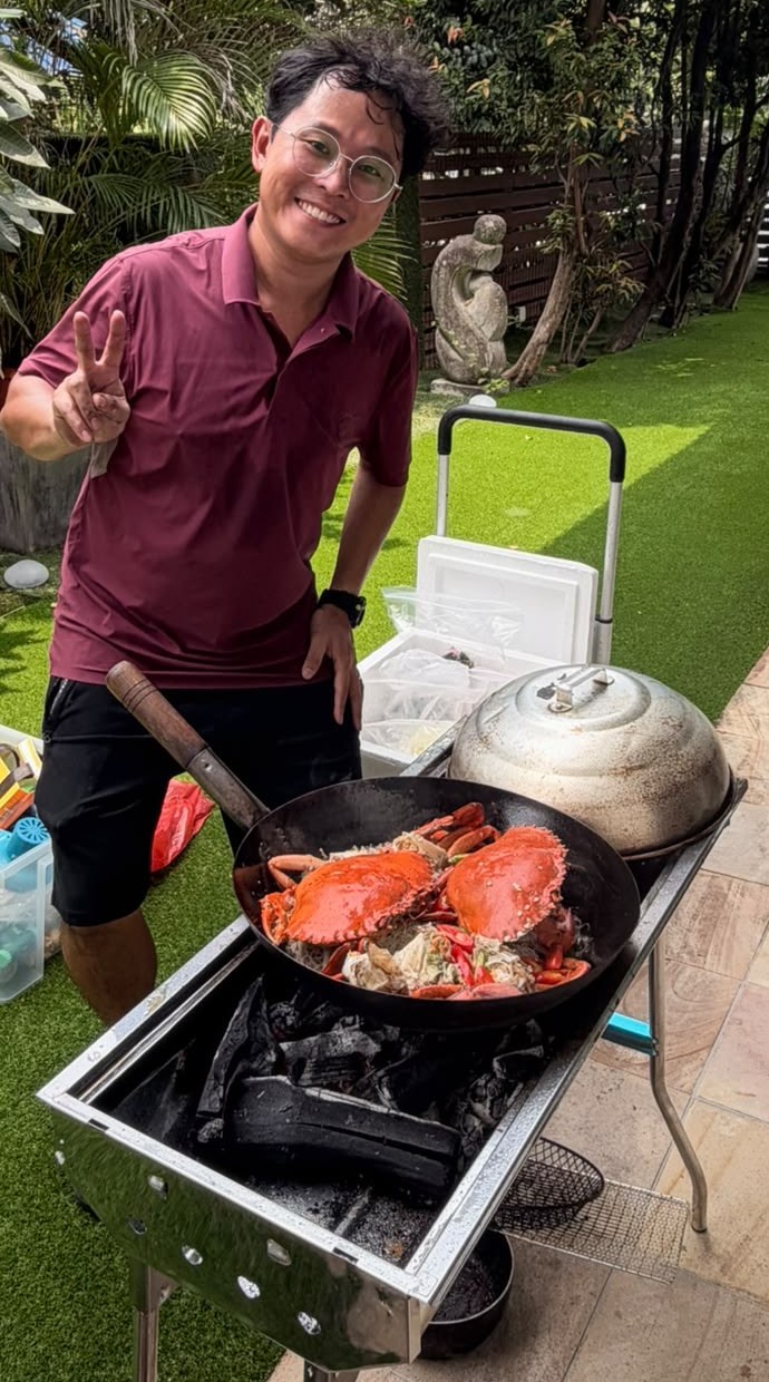 CharB chef cooking crab in a wok over a charcoal BBQ pit in a garden