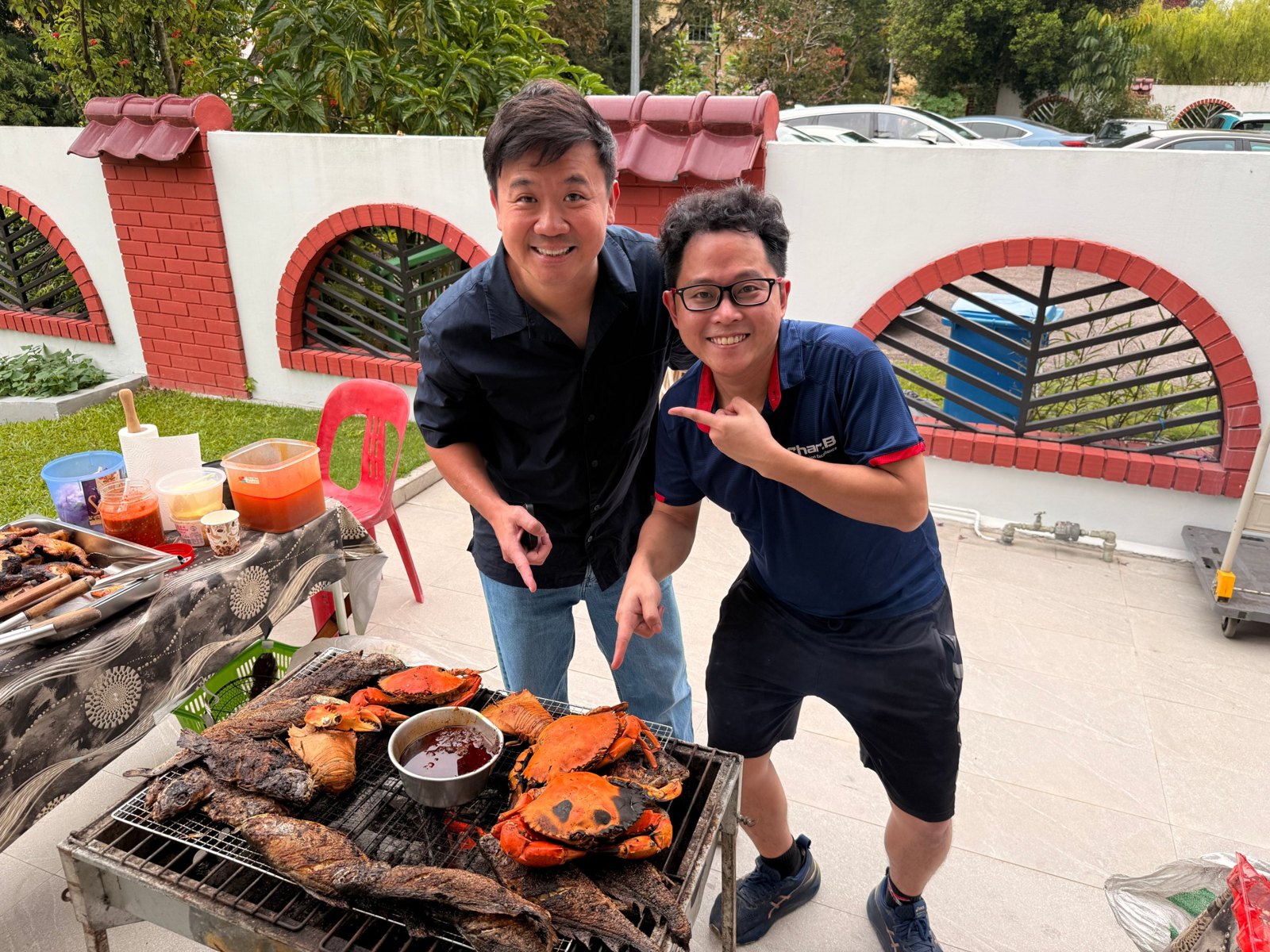 CharB chef with a guest beside a charcoal BBQ of crabs and fish