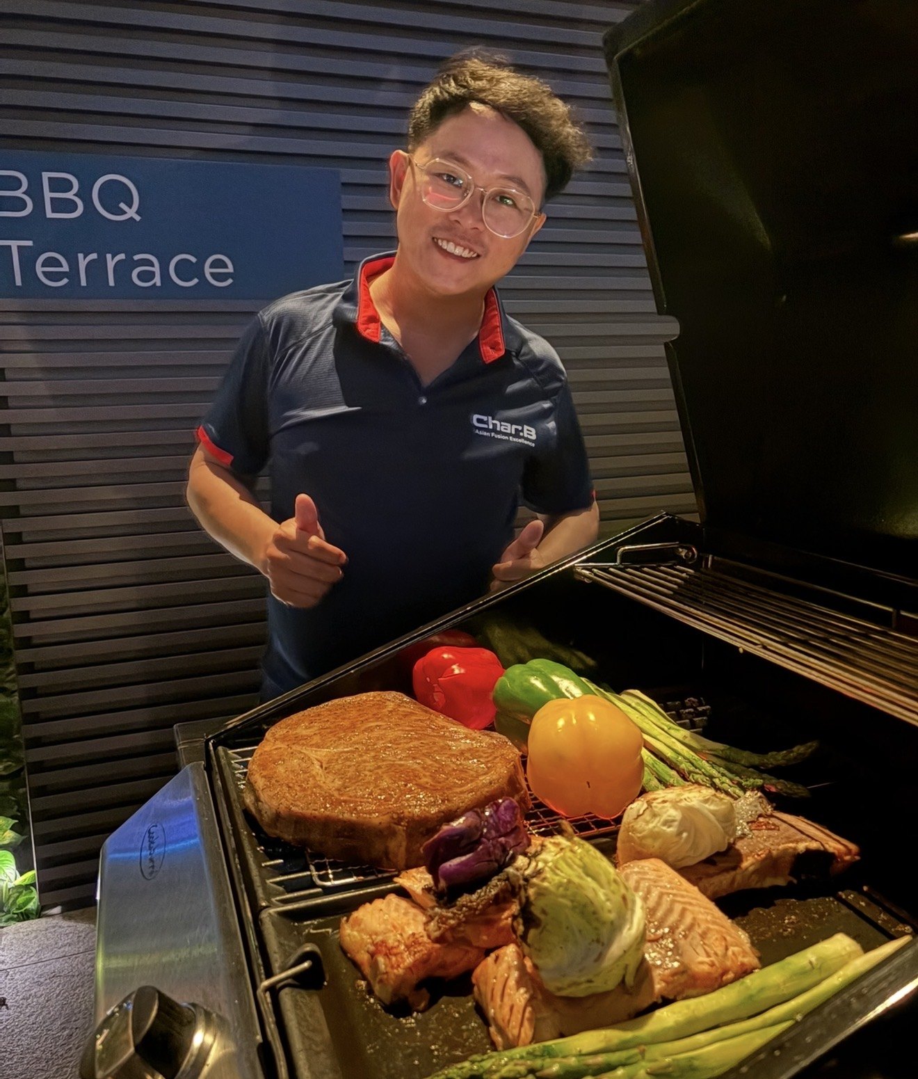 CharB chef with steak, salmon and vegetables on a gas grill at a BBQ terrace