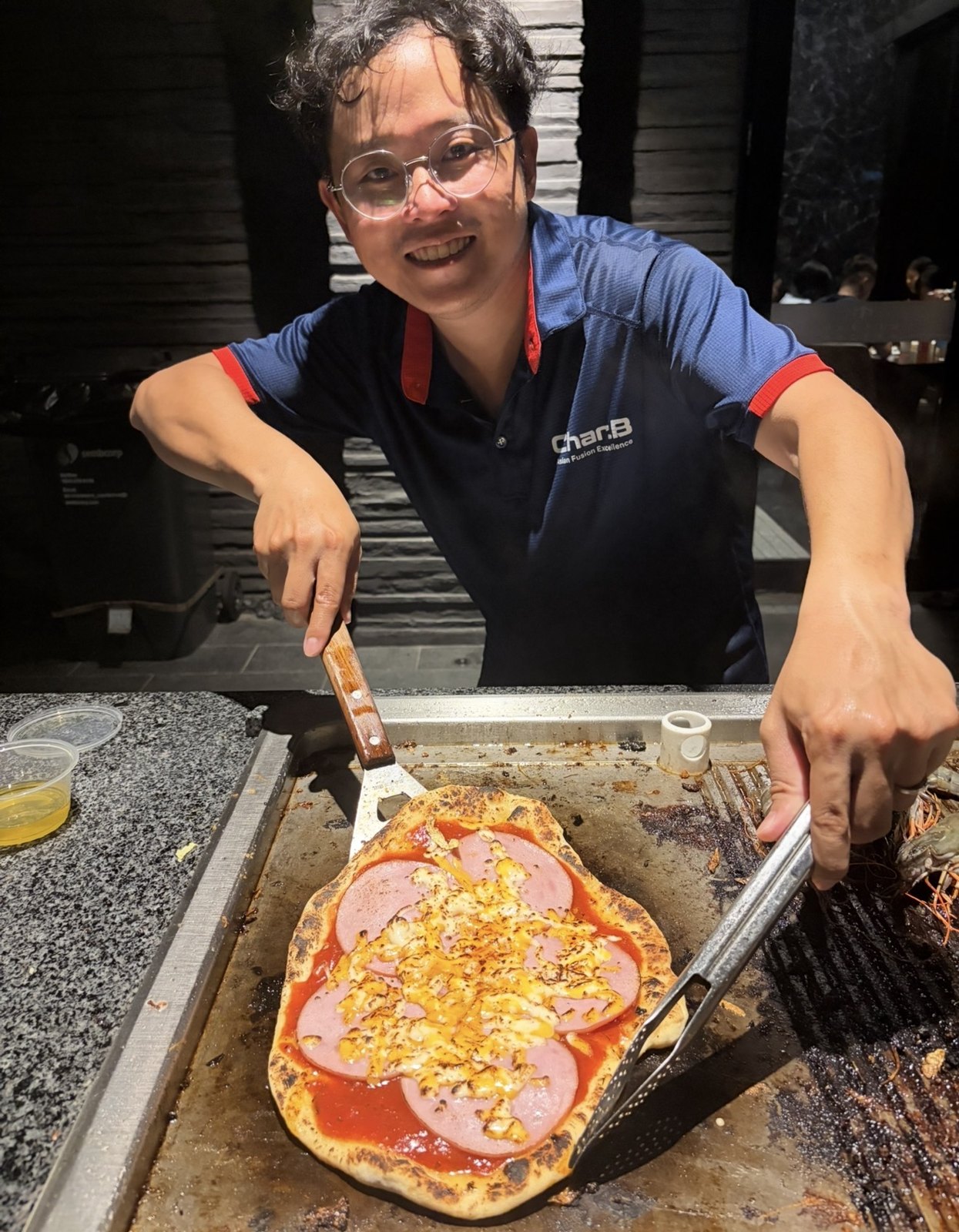 CharB chef serving a pizza cooked on a live griddle