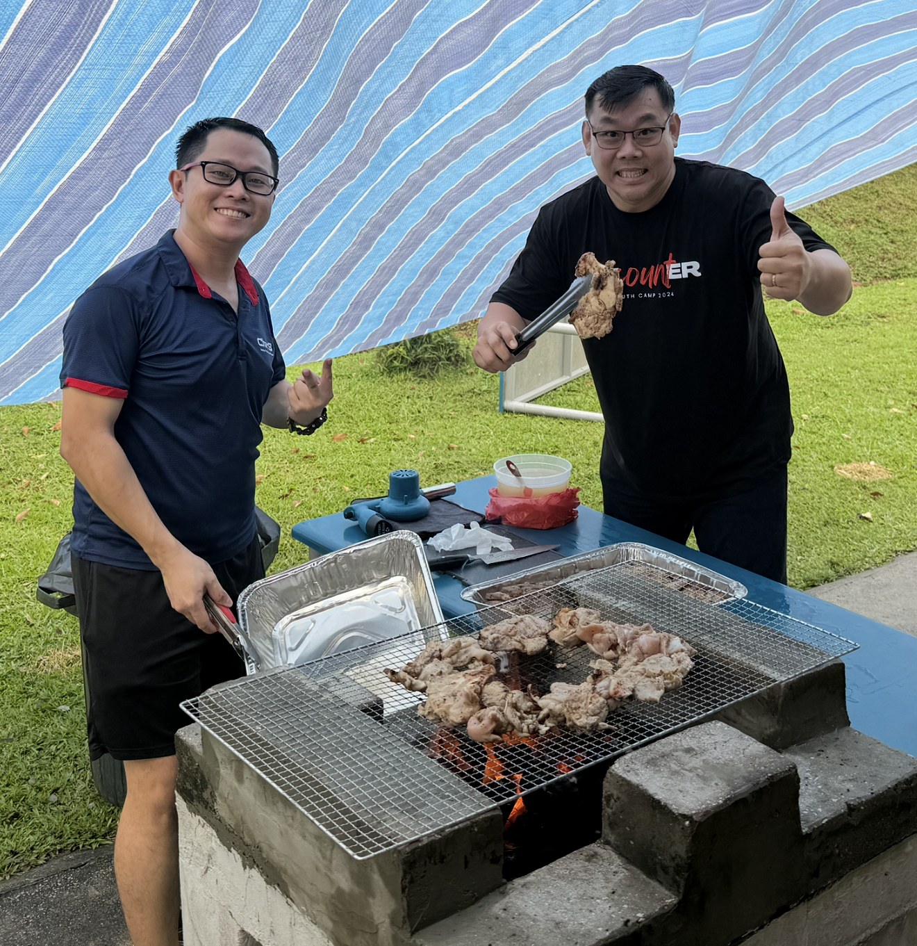 CharB grilling chicken on a charcoal BBQ pit at an outdoor event