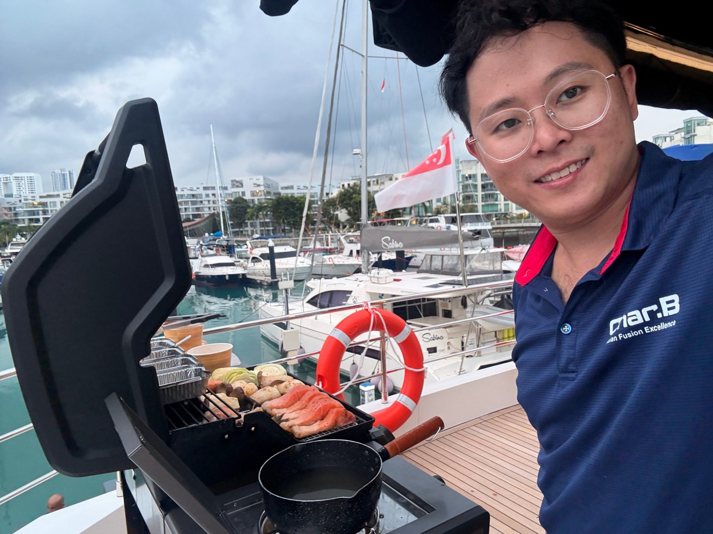 CharB chef grilling salmon and vegetables on the deck of a yacht at a Singapore marina